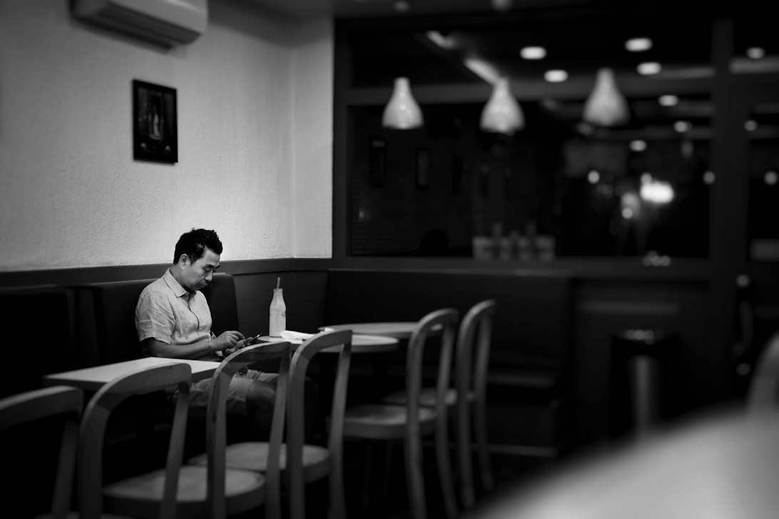 En enlig mand sidder ved et bord i en tom restaurant, hvilket skaber en melankolsk stemning.